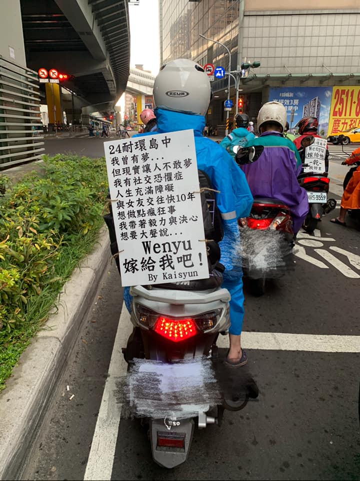 等紅燈發現隔壁「24小時耐力環島」向女友求婚！ 2兄弟義氣相挺「背上板子卻透露心聲」網笑歪